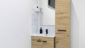 Un baño moderno con tocador de madera, un espejo y un lavabo blanco.