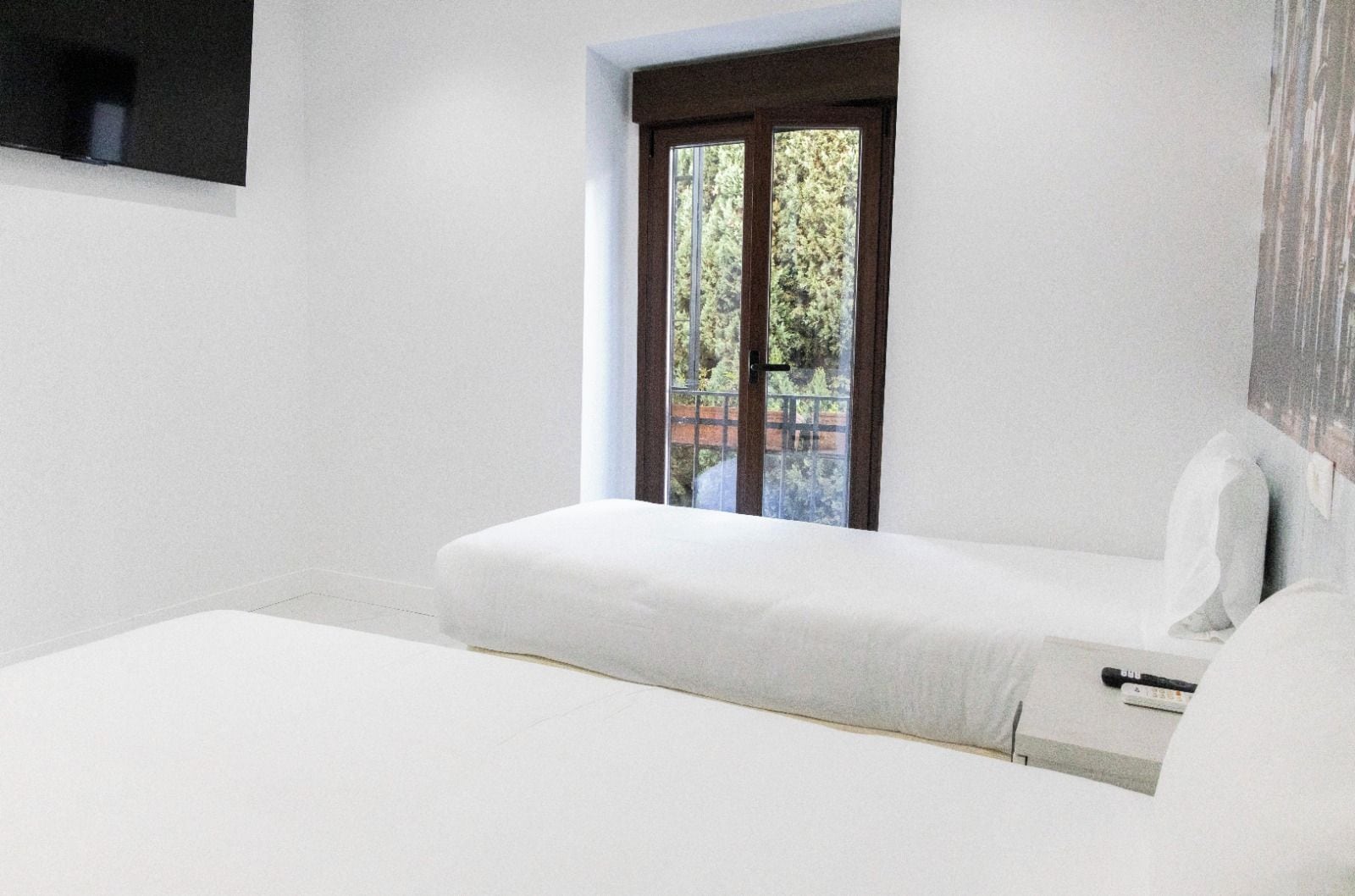 Une chambre à coucher au style minimaliste, avec une grande fenêtre, un lit et une table de chevet.