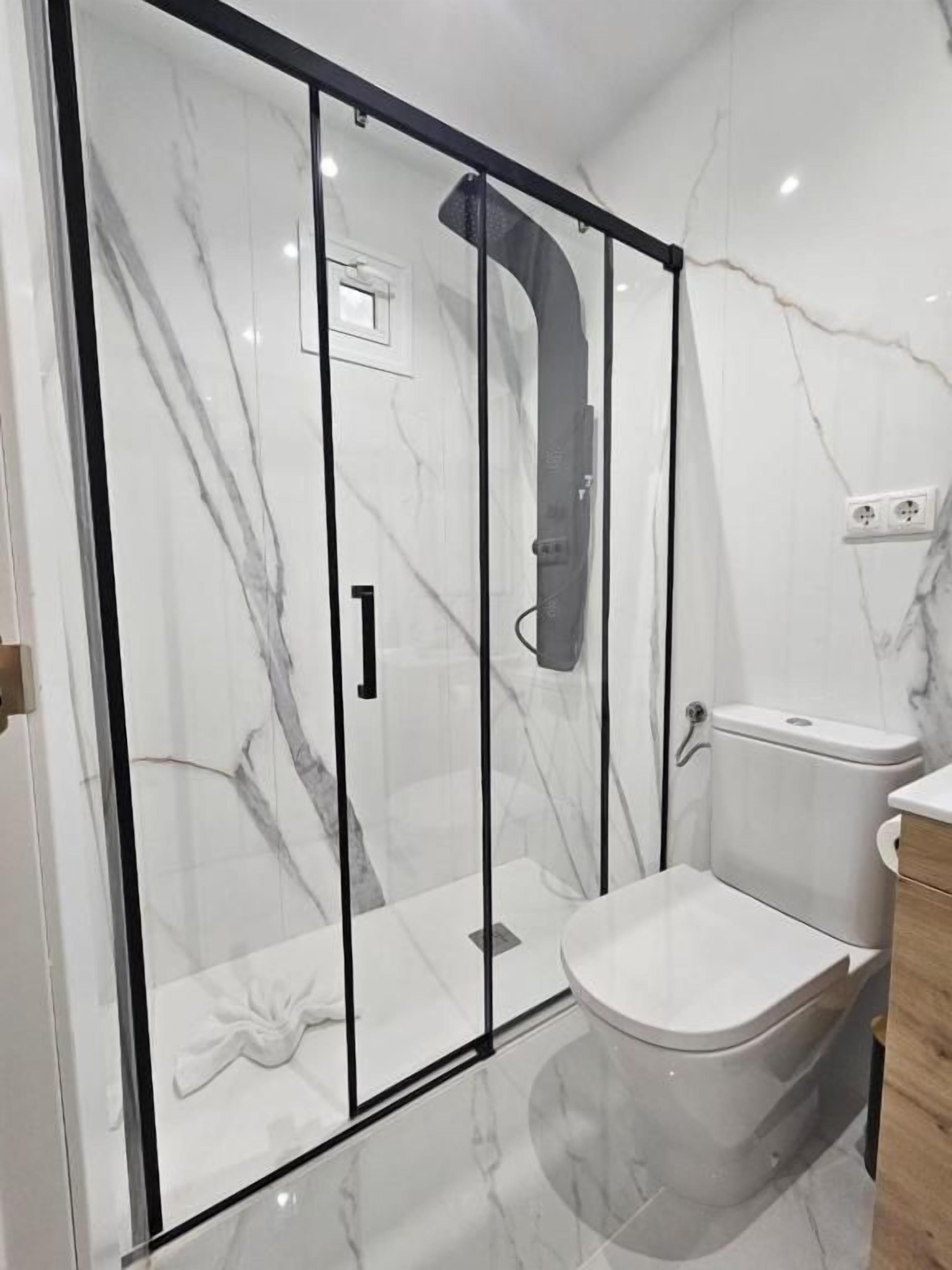Un baño moderno con ducha envuelta en vidrio, inodoro y lavamanos.