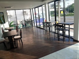 Interior de restaurante con diseño moderno, con mobiliario de madera y metal, ventanas amplias con vistas a la calle y piso de baldosas.