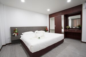 Habitación de hotel moderna con una cama grande, una mesita de noche, un espejo y un escritorio.