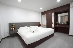 Une chambre d’hôtel moderne avec un grand lit, une table de chevet avec une lampe, une commode et un miroir.