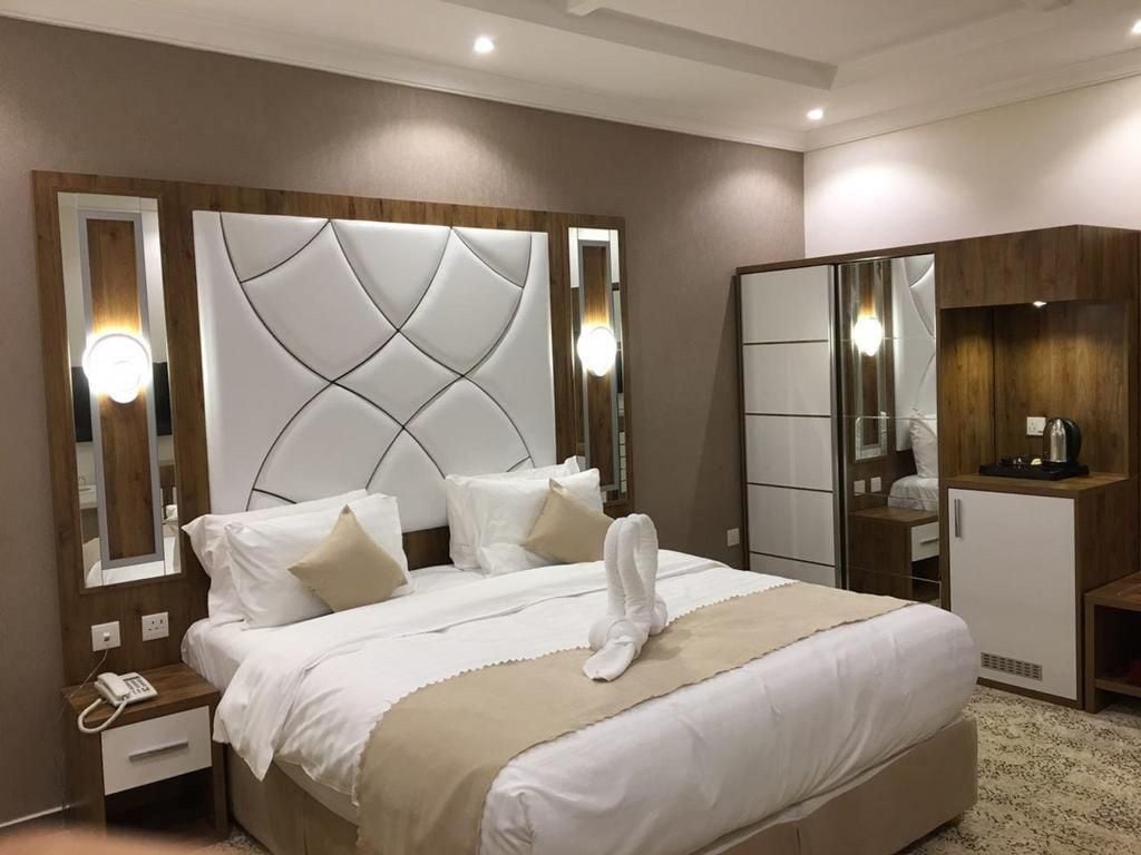 A hotel room with a large bed, bedside tables, a wardrobe, and a mirror.