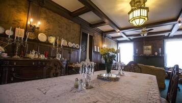 Ett rum med ett matbord dukat för fyra personer, en kristallkrona och en vas med blommor.