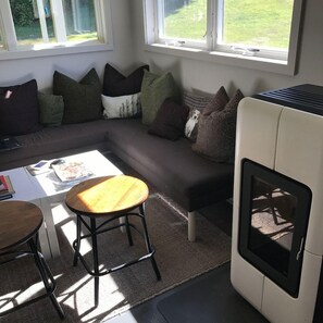 A modern living room with a sectional sofa, a round wooden coffee table, a small stool, and a built-in fireplace. - The Briarcliff Motel (Great Barrington)