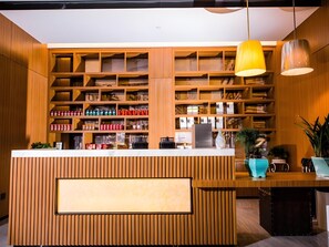 A reception desk with a wooden finish, a white counter, and a large hanging light fixture.
