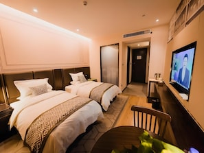 Une chambre d’hôtel avec deux lits, une télévision, un bureau et une chaise.