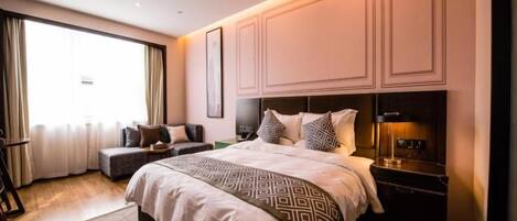 Habitación de hotel con una cama grande, una mesita de noche y un ventanal con cortinas.