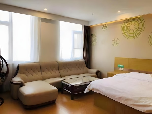 A hotel room with a sofa, a bed, a coffee table, and a wall with circular patterns.