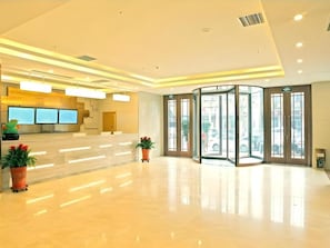 A hotel lobby with a reception desk, a glass revolving door, and potted plants. - Greentree Inn Baoding City Zhuozhou Railway Station Store (Baoding)