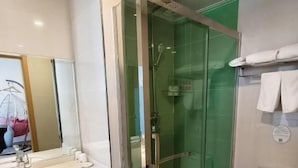 Um banheiro moderno com chuveiro em gabinete de vidro, vaso sanitário e pia.