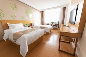 A hotel room with two beds, a desk, a television, and a small table with chairs.