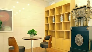 Um interior moderno com uma mesa redonda, duas cadeiras, um vaso de planta e um armário decorativo com vasos.
