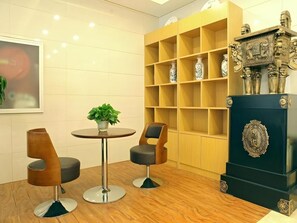 A modern interior with a round table, two chairs, a potted plant, and a decorative cabinet with vases. - Greentree Inn Baoding City Zhuozhou Railway Station Store (Baoding)