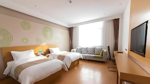 Quarto de hotel com duas camas, um sofá, uma televisão e uma escrivaninha.