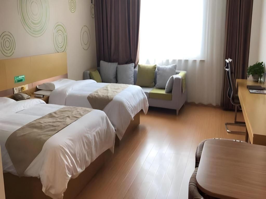 Ein Hotelzimmer mit zwei Betten, einem Sofa, einem Schreibtisch und einem Sessel.