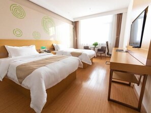 Ett hotellrum med två sängar, ett skrivbord, en TV och ett fönster med gardiner.
