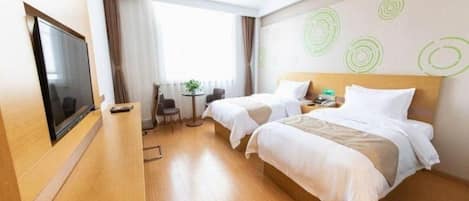 A hotel room with two beds, a TV, a desk, and a small table with a plant.