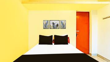 A hotel room with a bed, a door, and three wall-mounted pictures.