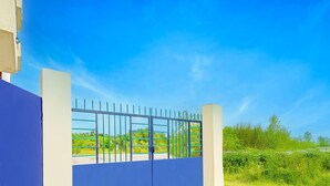 Ein verschlossenes Tor zu einem Anwesen mit blauem Himmel und viel Grün im Hintergrund.