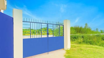 A gated entrance with a blue wall and metal gate, leading to a pathway.