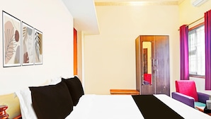 Ein Hotelzimmer mit Bett, Schreibtisch, Stuhl und Bildern an der Wand.
