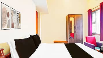 A hotel room with a bed, a desk, a chair, and a wardrobe.