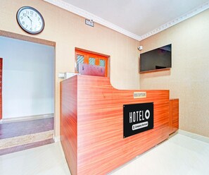 Un taulell de recepció d'hotel amb un rellotge a la paret.