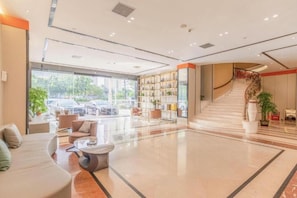 A spacious lobby with a seating area, a staircase, and a bookshelf. - Borrman Wanda Plaza Houjie Dongguan (Dongguan)