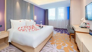 Een hotelkamer met een bed, nachtkastje, bureau, stoel en een televisie.