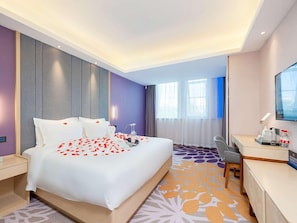 Une chambre d’hôtel comprenant un lit, une table de chevet, un bureau, une chaise et un téléviseur.