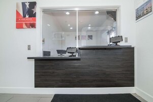 Una recepción con encimera de madera oscura, un separador de vidrio y un cartel en la pared.