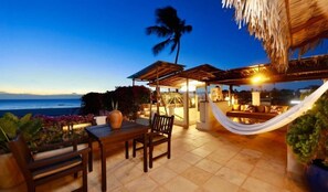 An outdoor seating area with a table and chairs, a hammock, and a view of the ocean at dusk. - Casa de Areia Jeri (Jijoca de Jericoacoara)