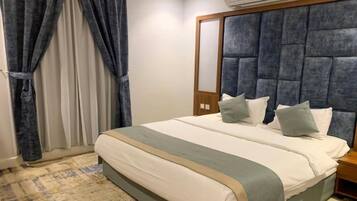 A hotel room with a large bed, a headboard, a bedside table, and a window with curtains.