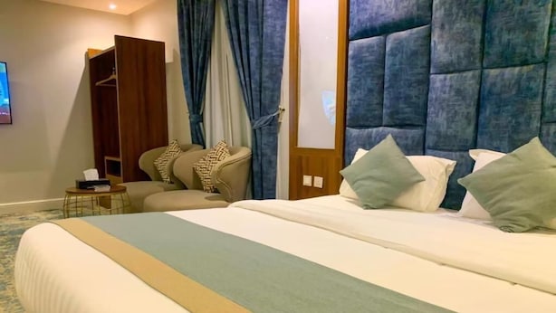 Habitació d'hotel amb un llit gran, un armari, zona de seients i televisió.