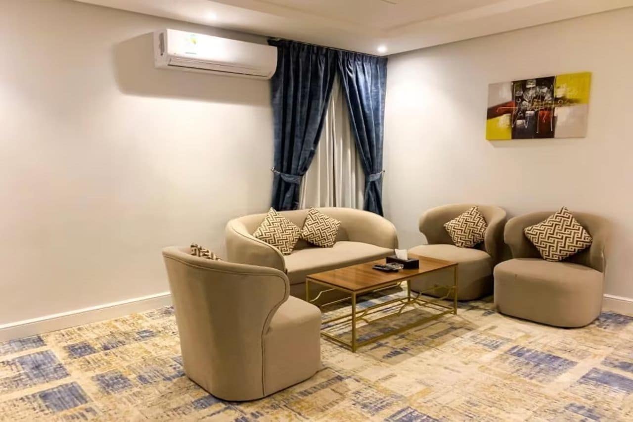 A living room with a sofa, armchairs, a coffee table, and a patterned rug.