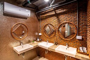 A bathroom with three sinks, a mirror, and a brick wall. - Kaen Hostel Pattaya (Pattaya)