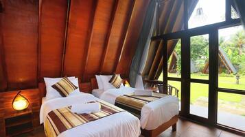 A room with two beds, wooden walls, and a large window.