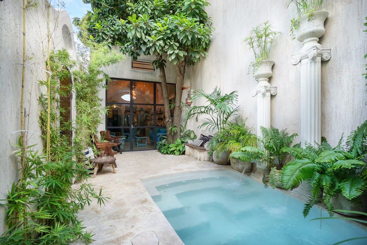 A courtyard with a pool, seating area, and various plants.
