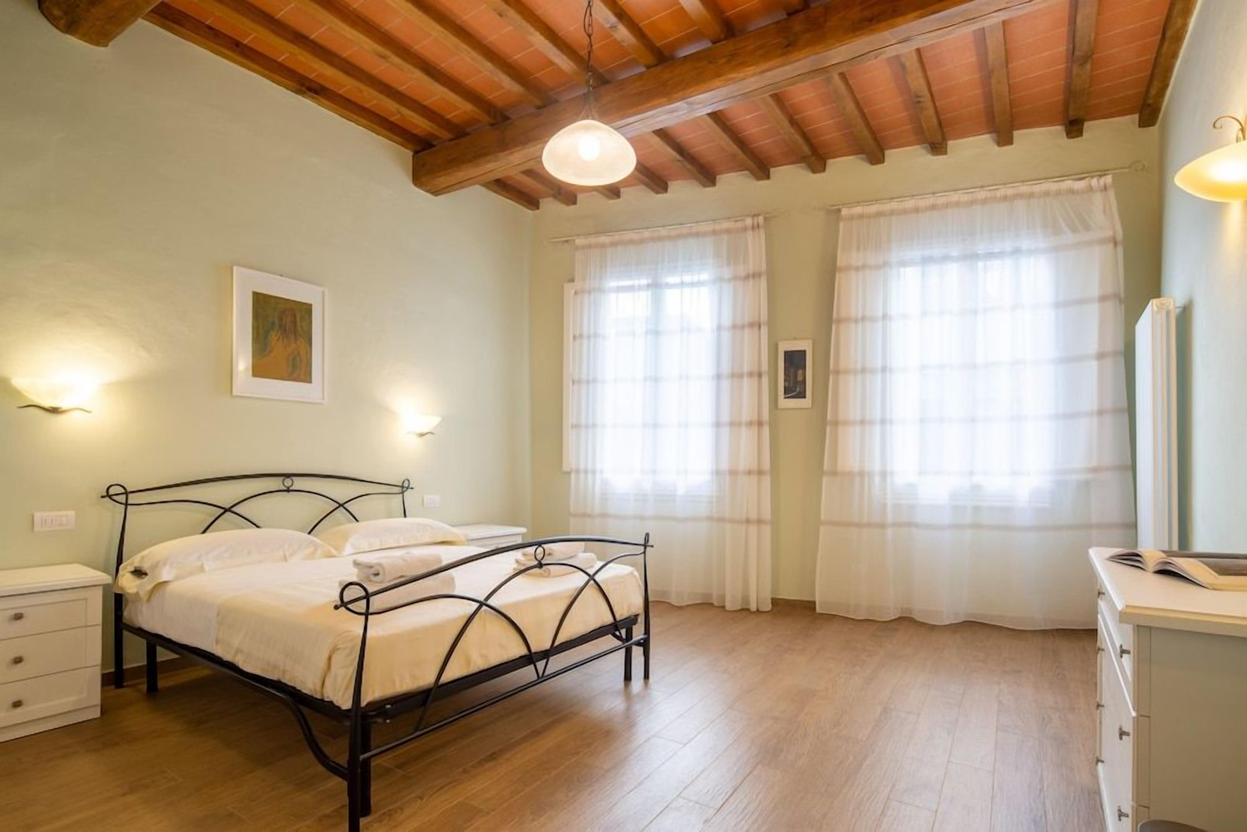 A bedroom with a bed, bedside tables, a dresser, and a ceiling fan.