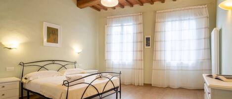 Un dormitorio con cama, mesitas de noche, cómoda y ventilador de techo.