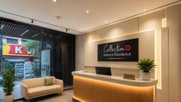 Un mostrador de recepción de hotel con diseño moderno, un letrero que dice 'Collection Havora Residence' y un sofá al frente.