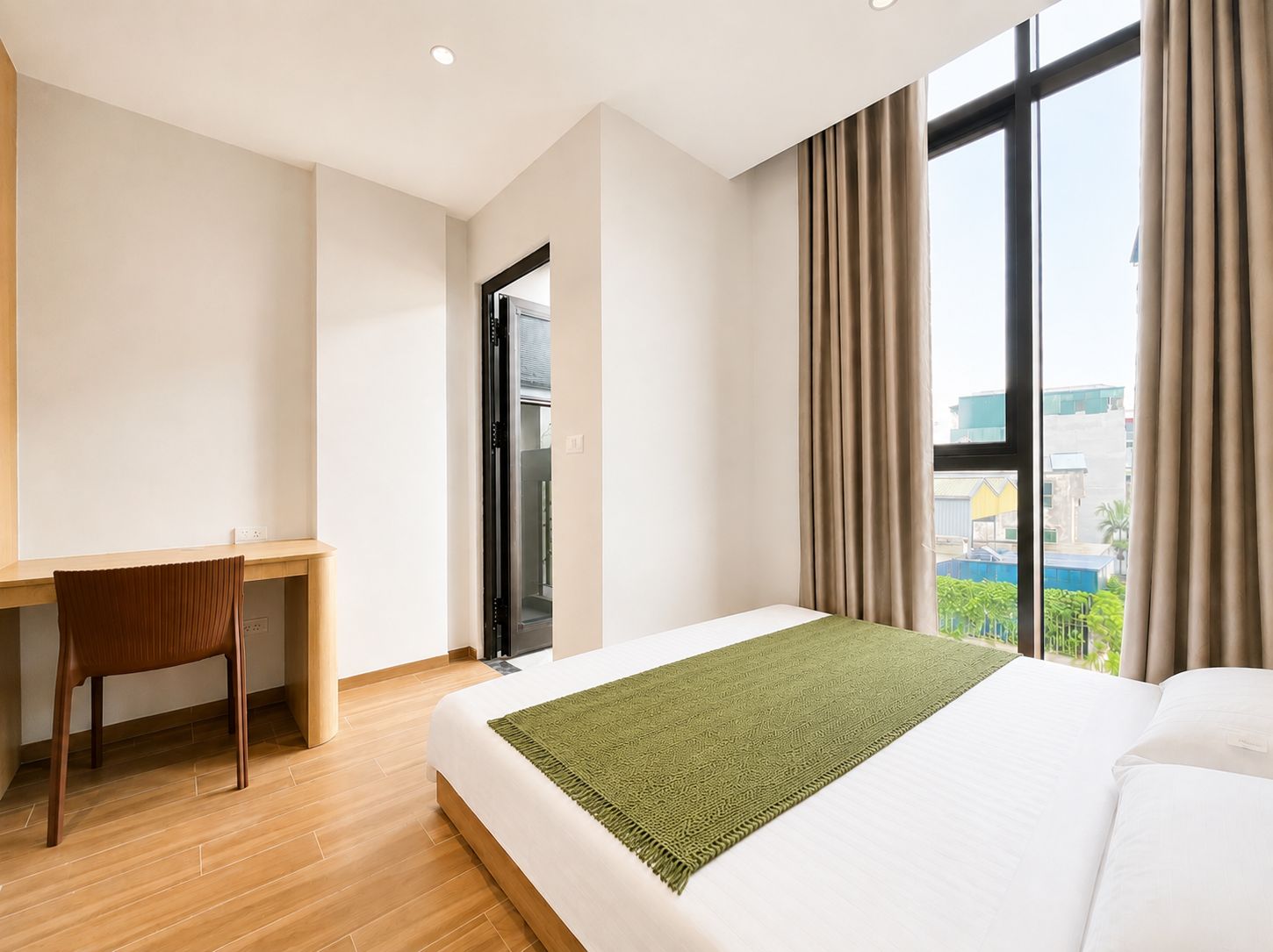 Una habitación de hotel con cama, escritorio y vista a la ciudad.