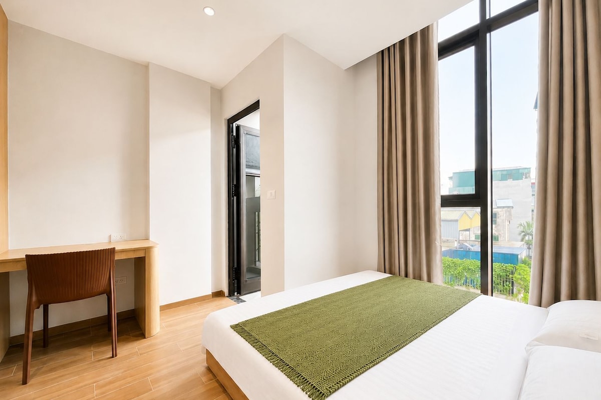Quarto de hotel com uma cama, uma escrivaninha e vista da cidade.