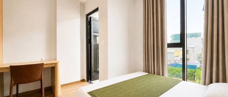 Une chambre d’hôtel avec un lit, un bureau et une vue sur la ville.