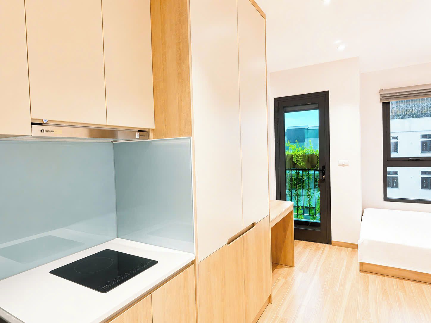 Quarto moderno com cama, escrivaninha embutida e vista para o exterior.
