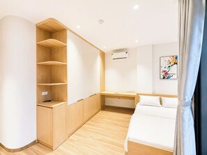 Quarto moderno com cama, guarda-roupa embutido, escrivaninha e ar condicionado.
