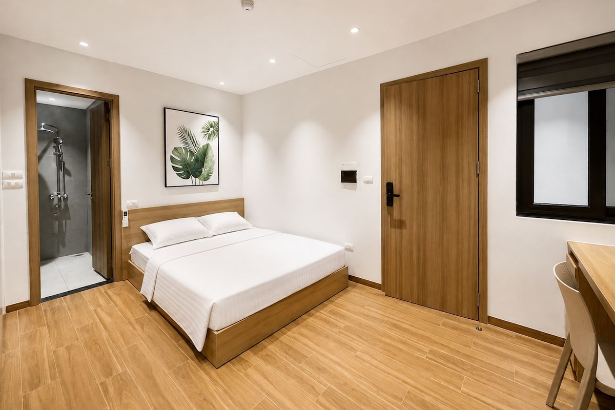 Quarto moderno com cama de madeira, chuveiro, porta de madeira e janela.