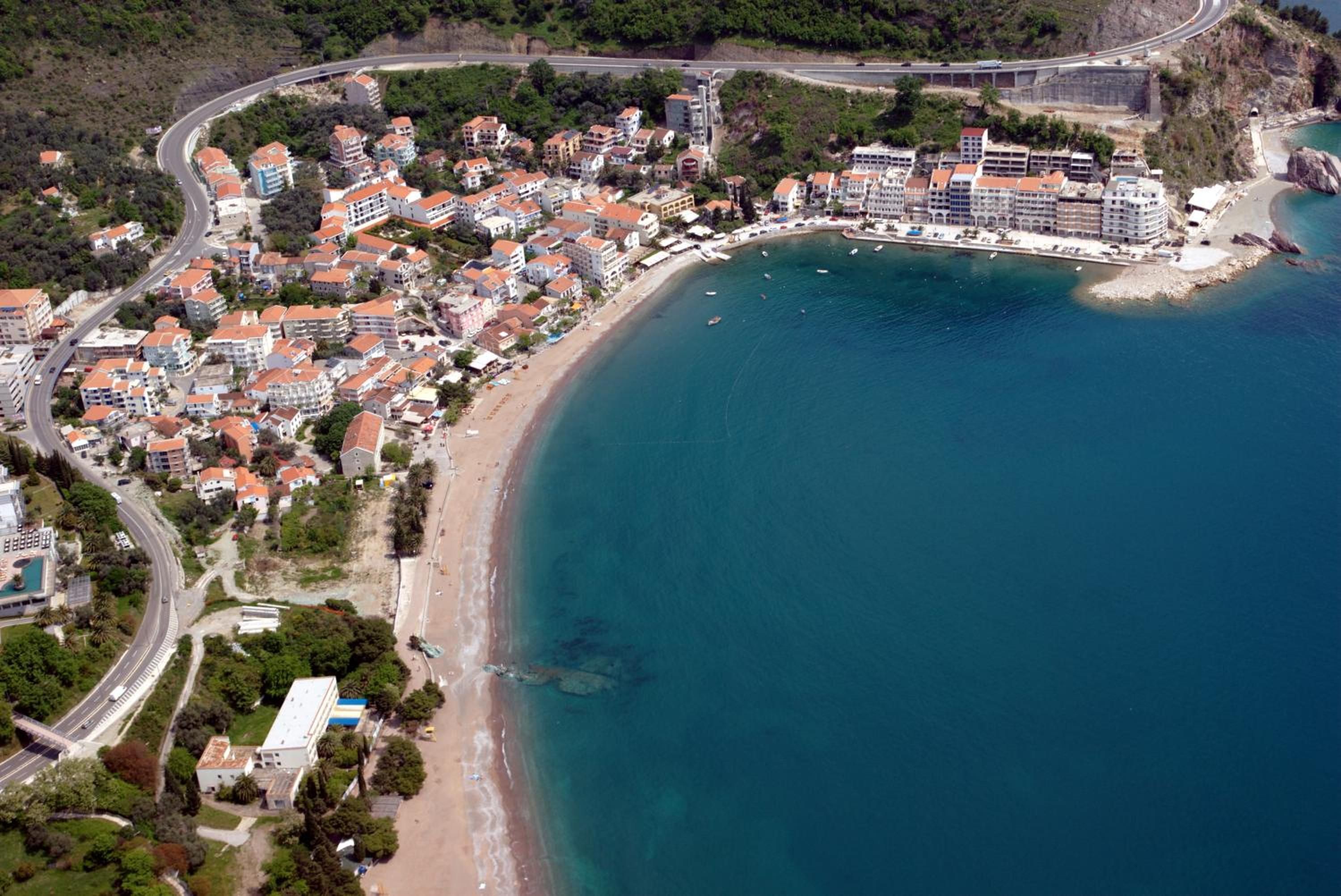 Une vue aérienne d’une ville côtière avec une plage, des bâtiments et une route.