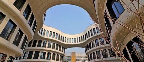 Ein modernes Gebäude mit einer gewölbten Fassade, zahlreichen Fenstern und blauem Himmel.